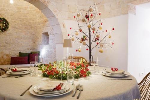 a dining room table with a tree with red flowers at Trullo Natù - private villa in Alberobello