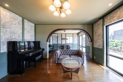 a living room with a piano and a couch at 尾道蝸牛 尾道駅から車でわずか10分 贅沢な広さと快適さを備えた滞在型旅館 無料駐車場3台有り supported by COCOSTAY in Mihara