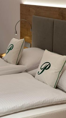 2 weiße Betten mit schwarzen und grünen Kissen darauf in der Unterkunft Hotel Gasthof zur Post Benediktbeuern in Benediktbeuern