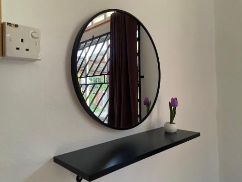 a mirror on a wall with a black shelf at Rumah Puteh Mersing Kecil ROOM FULLY AIR-CONDITIONED in Mersing