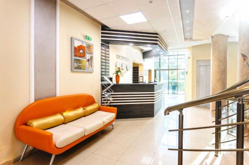 a waiting room with an orange couch in a lobby at Aparthotel Hotel Prestige City II in Primorsko
