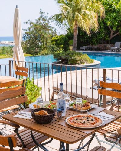 a table with two pizzas on it next to a pool at La Solenzara hôtel - 3 Etoiles Supérieur - Appartement & SPA in Sari Solenzara