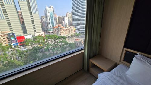 a bedroom with a window with a view of a city at Hotel R14 in Kaohsiung