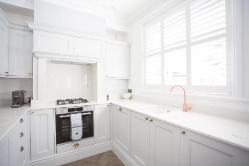 a white kitchen with white cabinets and a sink at Coachman's Cottage in Worthing
