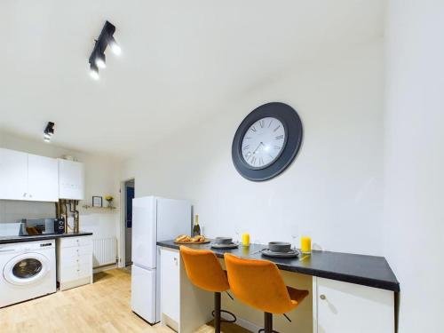 a kitchen with a table and a clock on the wall at NEW Portland House by Signature Stays - 3 Bedroom House in Cheltenham in Cheltenham