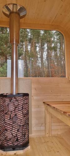 a fireplace in a log cabin with a window at BOSKO domki z sauną i balią w Sulminie obok Gdańska in Sulmin
