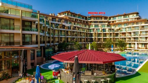 a hotel with a red umbrella in front of a building at Aparthotel Hotel Prestige City II in Primorsko