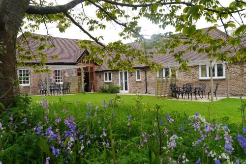 a brick house with flowers in the yard at 2 Moatside Cottages in Hassocks
