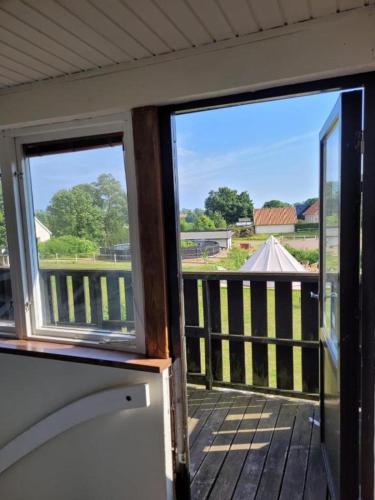 a porch with two windows and a view of a fence at Storstugan nära havet in Ystad