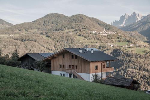 a house on a hill with mountains in the background at Oberhemberger Hof Feldthurns in Feldthurns