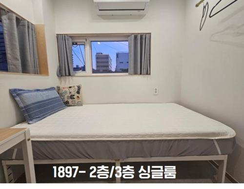 a bed in a small room with a window at Yachtie Inn 1897 in Mokpo
