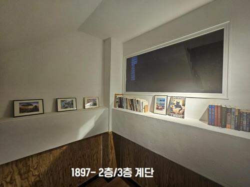 a living room with a tv and a shelf with books at Yachtie Inn 1897 in Mokpo