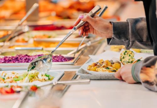 a person is serving food at a buffet at Ramada Hotel, Suites and Apartments by Wyndham Dubai JBR in Dubai