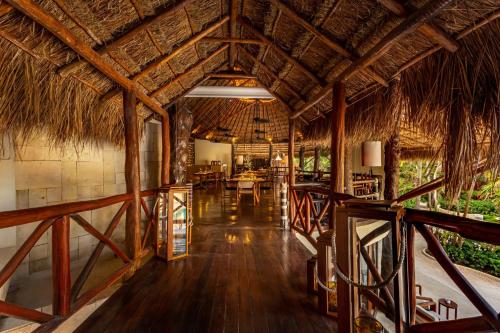 a dining area of a resort with a straw roof at Viceroy Riviera Maya, a Luxury Villa Resort - Adults Only in Playa del Carmen
