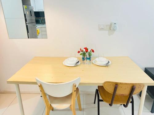 a wooden table with plates and flowers on it at Mercu Summer Suites Kuala Lumpur Bukit Bintang By Classy in Kuala Lumpur