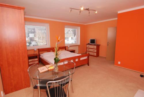 a bedroom with orange walls and a table and a bed at Apartmany Chodov in Prague
