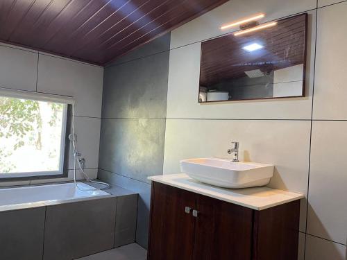 a bathroom with a sink and a mirror and a tub at Zyamadhari in Mananthavady