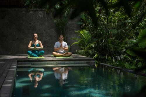 乌布Suweta Villa Ubud的坐在游泳池旁边的一对男女