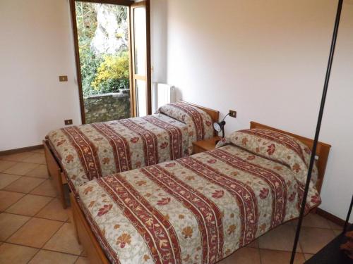 Dos camas en una habitación con ventana. en Exclusive Villa Crotto Lake View, en Varenna