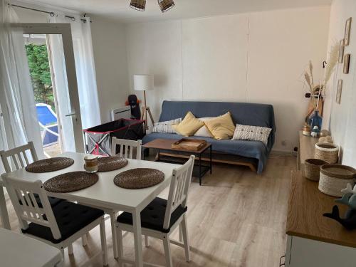ein Wohnzimmer mit einem Tisch und einem blauen Sofa in der Unterkunft Patrimoine et immobilier Villas du Lac in Soustons