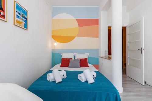 Cette chambre comprend un lit bleu avec des oreillers et un mur coloré. dans l'établissement 37 LAMARTINE - Magnifique Studio Art Deco - Centre-ville, à Nice