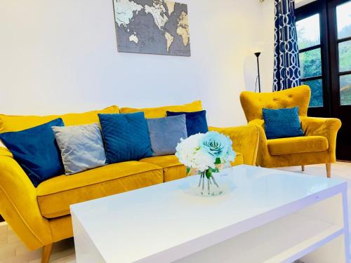 a living room with a yellow couch and blue pillows at Fairy Meadows Hideaway in Peterborough