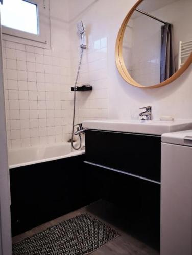 ein Badezimmer mit Badewanne, Waschbecken und Spiegel in der Unterkunft Appartement proche centre avec parking gratuit in Sèvres