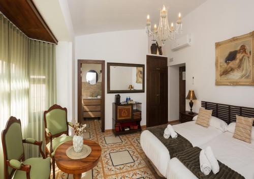 a bedroom with a bed and a table and a chandelier at Art Boutique La Casona de las Flores in Ondara