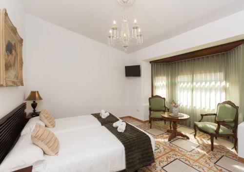 a bedroom with a bed and two chairs and a chandelier at Art Boutique La Casona de las Flores in Ondara