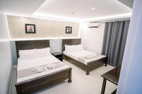 a hotel room with two beds and a table at Spotlight Hotel near Hundred Islands Wharf in Alaminos