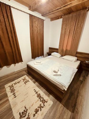 a bedroom with a bed with white sheets and a rug at Pool & Rest Holiday Home 3D in Bihać