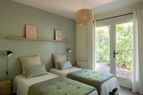 deux lits dans une chambre avec une fenêtre dans l'établissement Villa Chambrelent - Pyla sur Mer - proche de la plage, à La Teste-de-Buch