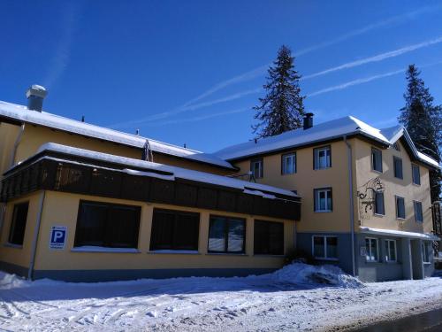 a yellow building with snow in front of it at Gasthof Hirschen in Langenegg