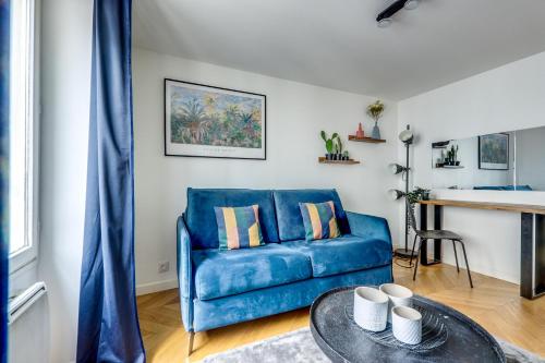 un canapé bleu dans un salon avec une table dans l'établissement T2 à 10min de Paris l Proche des Transports, à Charenton-le-Pont