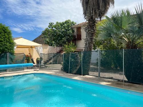 a swimming pool in a yard with a fence at Le colibri bleu in Argeliers