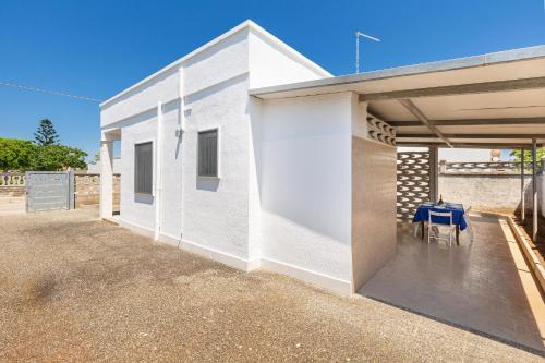 a white house with a blue table on a patio at Villetta Nini' by BarbarHouse in Punta Prosciutto