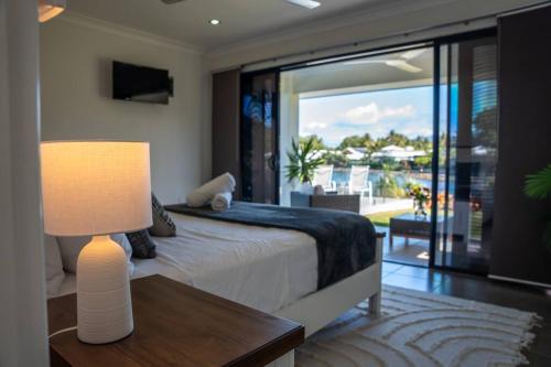 a bedroom with a bed with a lamp and a balcony at Lakeside Luxury, stroll to beach & restaurants- Pets Welcome in Trinity Beach