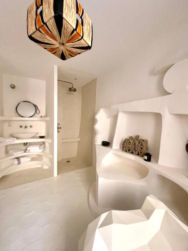 Cette chambre blanche est dotée d'un lustre et d'un canapé blanc. dans l'établissement Maison Bellevue, à Gassin