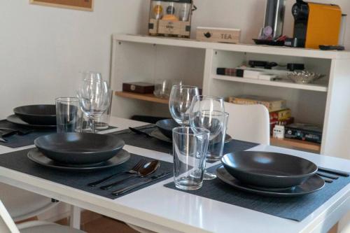 a table with black plates and glasses on it at Luminoso Bilocale 5 Minuti da Linate in Pioltello