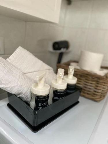 a shelf with three bottles of lotion and a bed at Luminoso Bilocale 5 Minuti da Linate in Pioltello