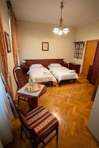 two beds in a room with a table and chairs at Pałac Sieniawa in Sieniawa