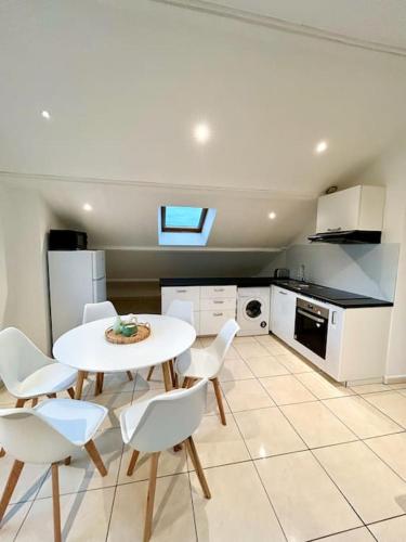 - une cuisine avec une table blanche et des chaises blanches dans l'établissement Espace cosy - Zénith & Atlantis, à Saint-Herblain