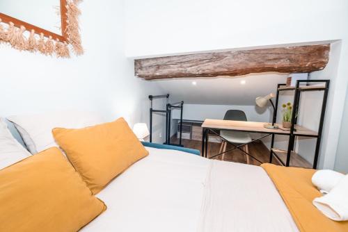 Cette chambre comprend un lit avec des oreillers jaunes et un bureau. dans l'établissement Marie-Rose au Faubourg - Charmant studio en plein cœur de Montauban, à Montauban