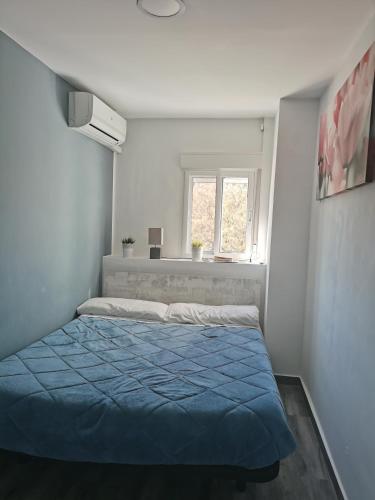 a bedroom with a blue bed and a window at Plaza Sainetero in Valencia