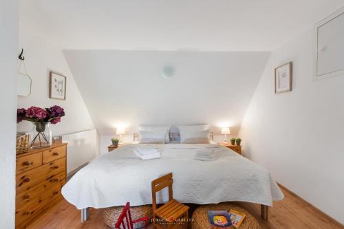 a white bedroom with a large bed and a dresser at Dornröschen 1 in Steinberg