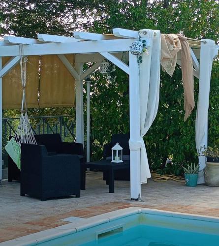 a white pergola with a swing and a pool at L'Isola Felice e Trulli Sotto Le Stelle in Castellana Grotte