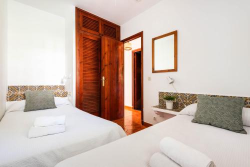 a bedroom with two beds and a mirror at Apartamentos en Son Bou in Son Bou