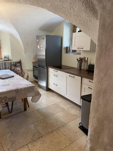 a kitchen with a stainless steel refrigerator and a table at MAISON CARAIL Névache 14 personnes in Névache