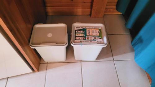 two trash cans sitting on the floor in a bathroom at Reflet de Bien Être in Marsoulas