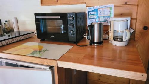 a kitchen counter with a microwave and a coffee maker at Reflet de Bien Être in Marsoulas
